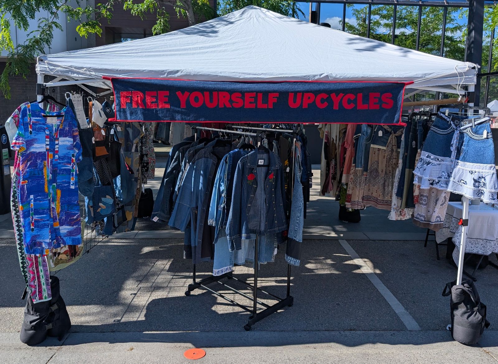 Free Yourself Upcycles market booth with the hand-embroidered banner